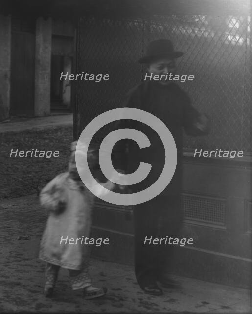 Man and a young child walking down a street, Chinatown, San Francisco, between 1896 and 1906. Creator: Arnold Genthe.