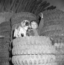 A boy with his dog on top of a pile of tyres imported from the USA, Sweden, c1940s(?). Artist: Otto Ohm