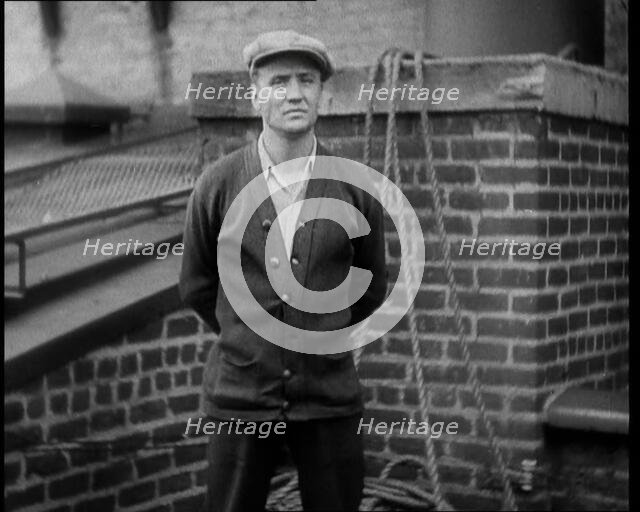 Male Civilian Wearing a Cardigan and a Flatcap Standing in Front of a Wall Talking at the..., 1930. Creator: British Pathe Ltd.