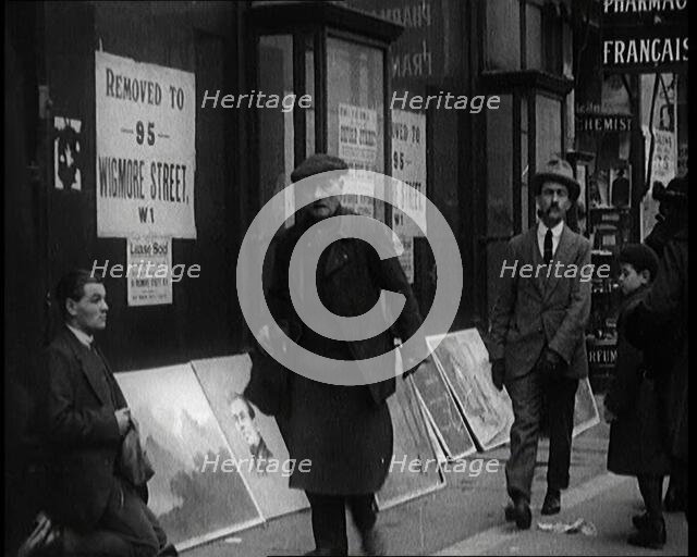 Male Ex-Services Civilian Selling Paintings on a Pavement Whilst Other Civilians are Walk..., 1920s. Creator: British Pathe Ltd.
