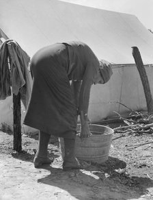 A grandmother washing clothes in a migrant camp, Stanislaus County, California, 1939. Creator: Dorothea Lange.