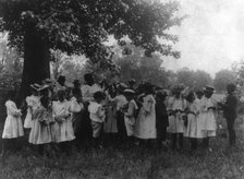 African American school children and teacher, studying leaves out of doors, (1899?). Creator: Frances Benjamin Johnston.