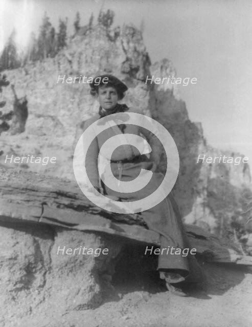 Frances Benjamin Johnston, full-length portrait, sitting on ledge with..., between 1888 and 1920. Creator: Frances Benjamin Johnston.