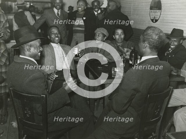 African Americans conversing and drinking beers in a bar, Clarksdale, Mississippi Delta, Nov 1939. Creators: Farm Security Administration, Marion Post Wolcott.