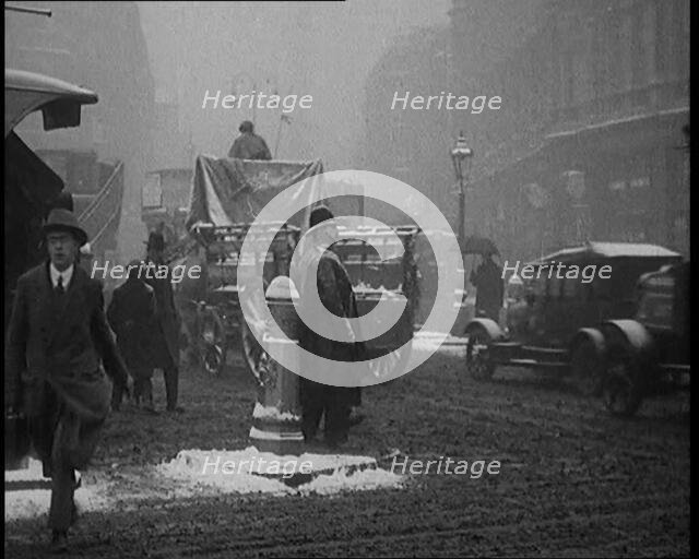 British Civilians Going About their Daily Commute on a Snowy Day on the Streets Watched by..., 1920. Creator: British Pathe Ltd.