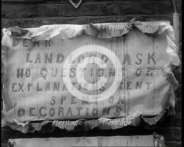 Poster Hanging on Wall Reading 'DEAR LANDLORD ASK NO QUESTIONS OR EXPLANATIONS RENT SPENT..., 1937. Creator: British Pathe Ltd.