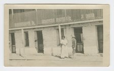 Photograph of a man and woman standing on a sidewalk, early 20th century. Creator: Unknown.