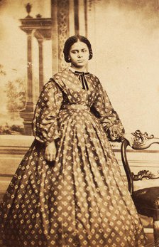 Portrait of young woman wearing patterned dress, with bow at neck, c1860. Creator: Coss & Leach.