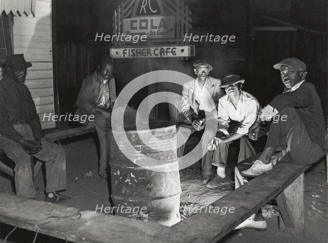 Negro laborers sitting around in front of a fire on Saturday night in a street of the..., Feb 1941. Creators: Farm Security Administration, Marion Post Wolcott.