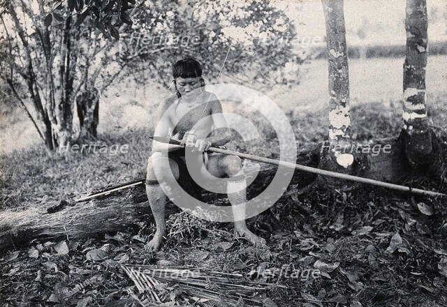 Sarawak: a Kenyah worker tying a spearhead to a blowpipe, c1900. Creator: Unknown.