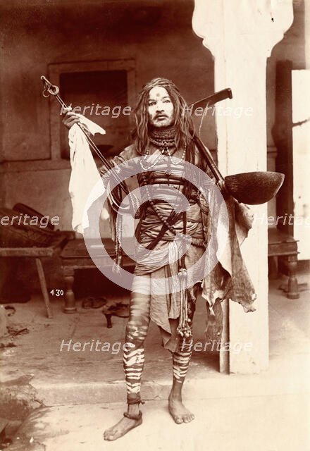 A young Indian man wearing many beads and makeup in a temple precinct, c1900. Creator: Unknown.