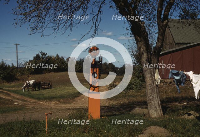Gas pump with clothesline, barn and horse-drawn wagon in background, between 1941 and 1942. Creator: Unknown.