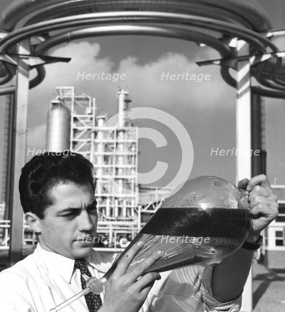 A laboratory worker holds a separating funnel of oil, Dunkirk refinery, France, 1950s. Artist: Unknown