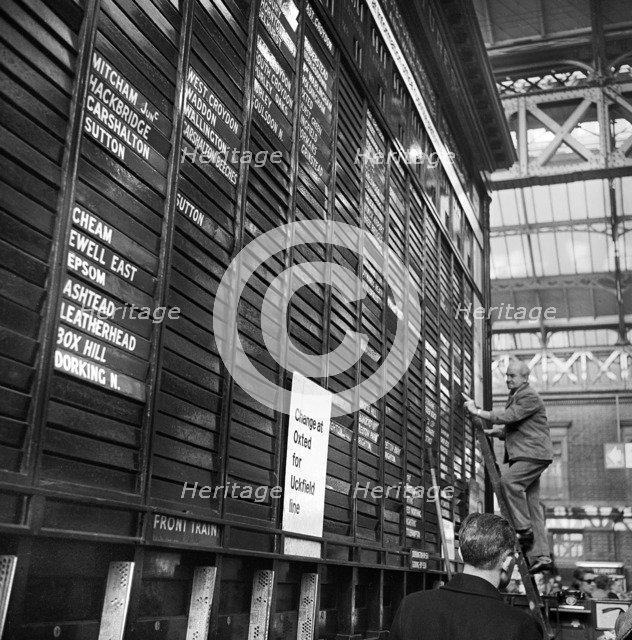 Repairing the departure board at Victoria Station, London, 1960-1972. Artist: John Gay