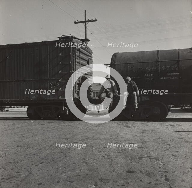 Colored itinerants on oil tank cars passing through Kingsbury, California, 1938. Creators: Farm Security Administration, Dorothea Lange.