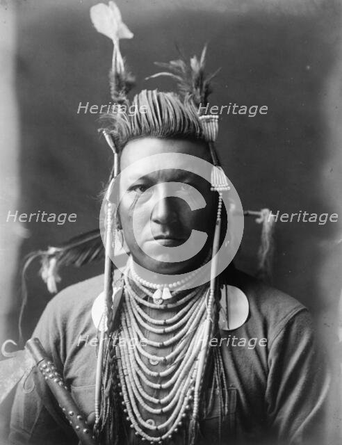 Swallow Bird, Crow Indian, Montana, head-and-shoulders portrait, facing front, painted..., c1908. Creator: Edward Sheriff Curtis.