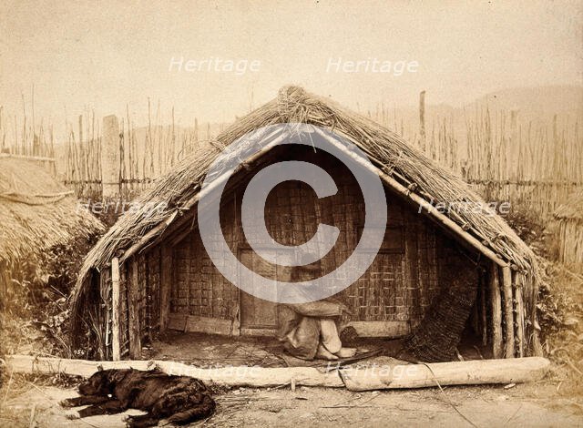 New Zealand: a Maori man sitting in front of a traditional house, between 1800 and 1899. Creator: Unknown.