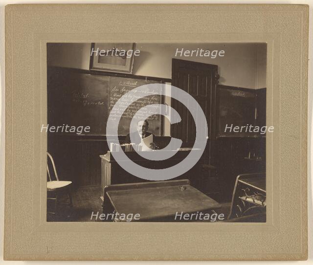 Portrait of a male mathematics teacher with moustache seated at his classroom desk, about 1900. Creator: Unknown.