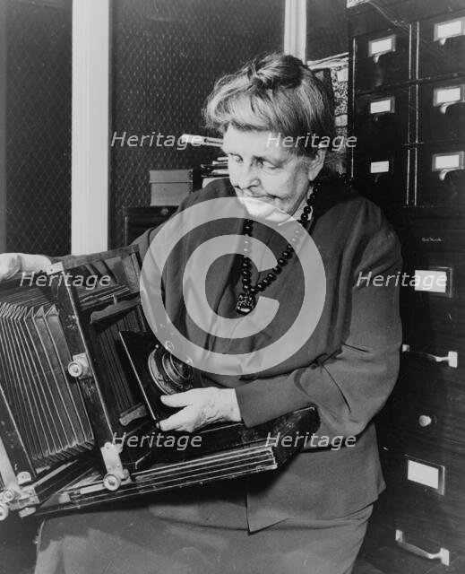 Frances Benjamin Johnston, three-quarter length portrait, holding and looking down..., c1950. Creator: Unknown.
