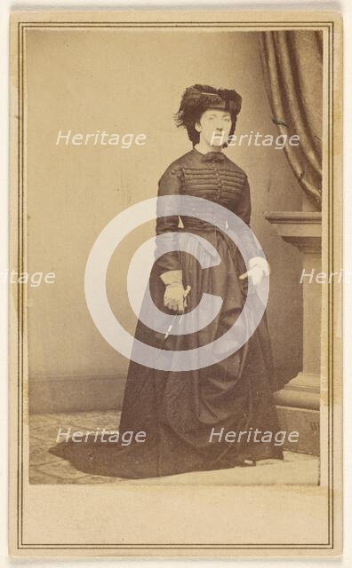 Unidentified woman wearing a hat and long dark dress, about 1868. Creator: Mathew Brady.