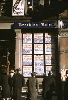 Men and a woman reading headlines posted in street-corner window of Brockton..., Mass., 1940. Creator: Jack Delano.