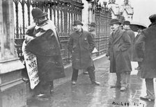 A policeman removes a suffragette poster from the railings, House of Commons, London, March 1909. Artist: Unknown