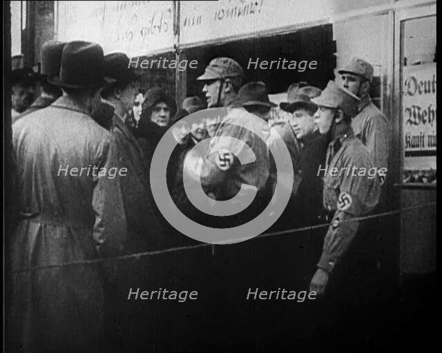Men in Nazi Uniforms and Civilians Standing Outside a Shop With anti-Jewish Posters on it, 1933. Creator: British Pathe Ltd.