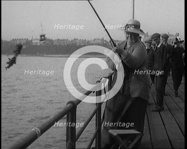 Female Civilian Wearing a Hat with a Dark Ribbon Fishing from a Pier, 1920. Creator: British Pathe Ltd.