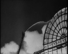 A Firefighter on a Ladder Trying to Extinguish the Crystal Palace Fire, 1936. Creator: British Pathe Ltd.