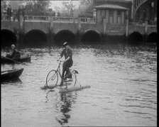 Woman Riding Along a River on a Floating Bicycle Contraption, 1920. Creator: British Pathe Ltd.