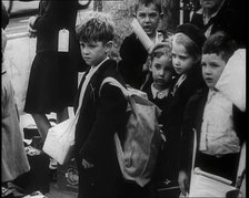 British Child Evacuees Standing on a Pavement With Bags and Boxes as Adults are Standing..., 1939. Creator: British Pathe Ltd.