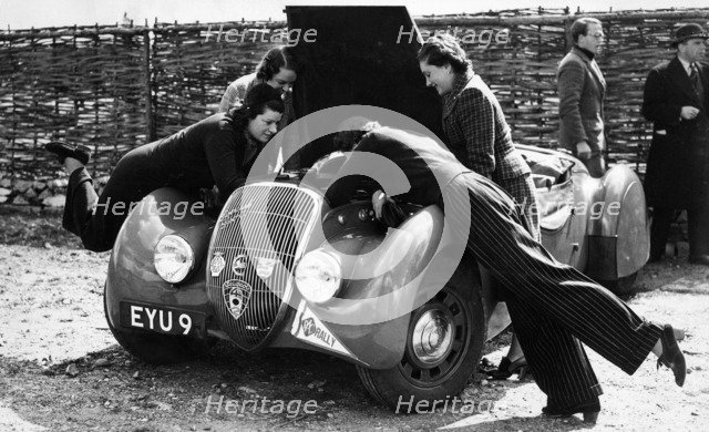 Miss MD Patten looking at the engine of a 1938 Peugeot 402 Special Sport, RAC Rally, 1939. Artist: Unknown