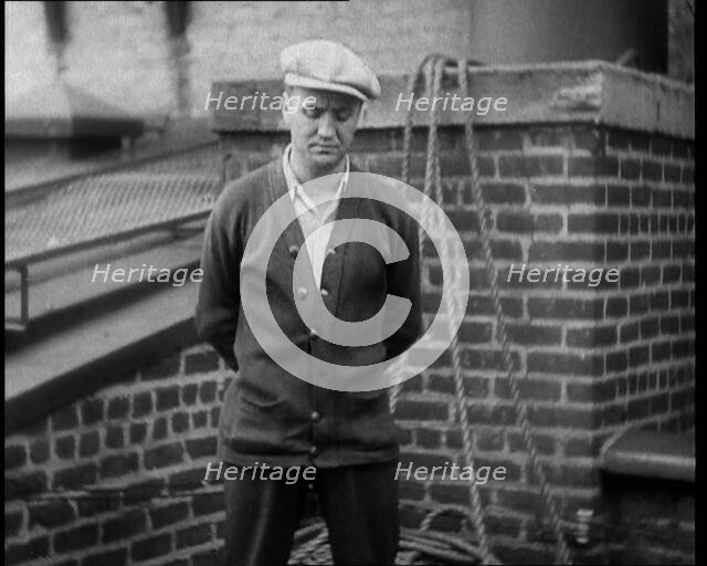 Male Civilian Wearing a Cardigan and a Flatcap Standing in Front of a Wall Talking at the..., 1930. Creator: British Pathe Ltd.