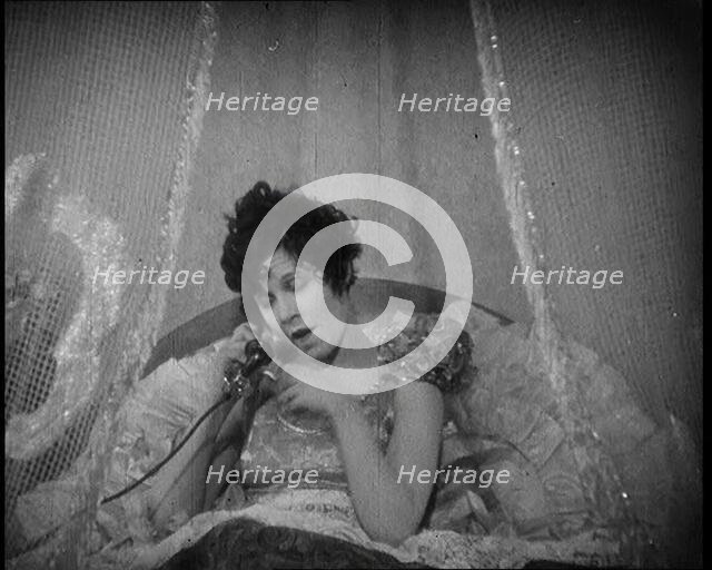 Scene from a 1920s Film. A Female Actor Speaking on the Telephone in Bed Still Wearing Her..., 1920s Creator: British Pathe Ltd.