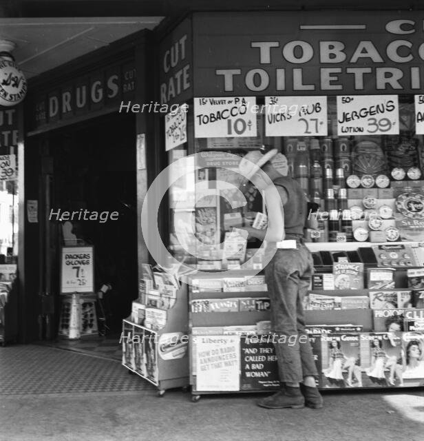 Half-grown farm boy on main drugstore corner in town, Medford, Oregon, 1939. Creator: Dorothea Lange.
