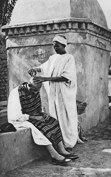 A street barber and his client, Algeria, Africa, 1922.Artist: Donald McLeish