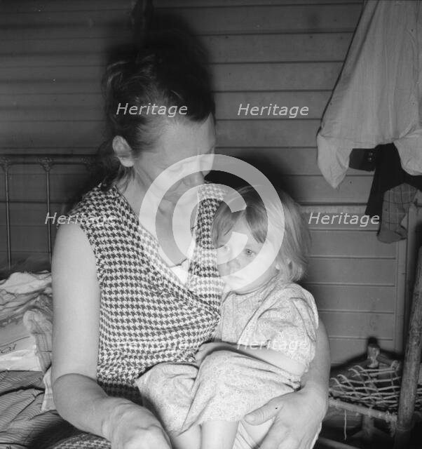 Mother from Oklahoma, awaits visit of resident nurse for sick baby, FSA camp, Farmersville, CA, 1939 Creator: Dorothea Lange.