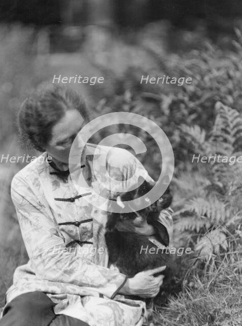 Egger, Gabrielle, Miss, friend of, with cat, seated outdoors, between 1926 and 1930. Creator: Arnold Genthe.