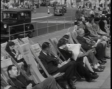 British Holidaymakers Sitting on Deckchairs on the Promenade at Brighton and Cars Driving..., 1938. Creator: British Pathe Ltd.