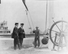 New York Yacht Club, Oyster Bay, L.I., 1905: 2 men watching sailor hoist flag, 1905. Creator: Frances Benjamin Johnston.