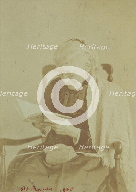 Elderly woman seated and reading a book with knitting in her lap, 1895. Creator: Horace L Bundy.