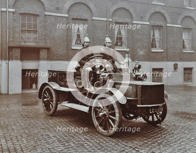 Firemen in brass helmets aboard a motor hose tender, London Fire Brigade Headquarters, London, 1909. Artist: Unknown.