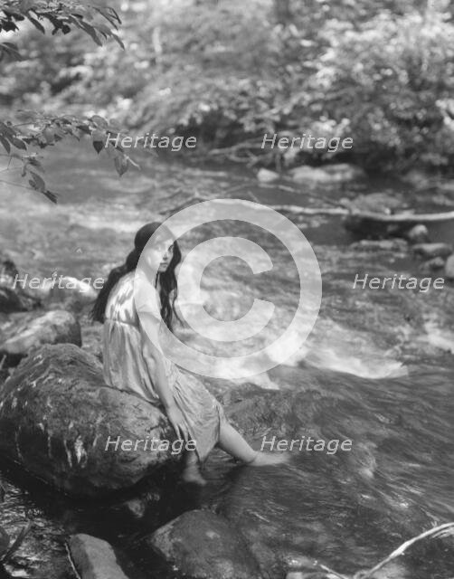Cowan, Rosamonde, Miss (Rose Rolanda ; Mrs. Miguel C.), seated by a stream, 1919 May 24. Creator: Arnold Genthe.