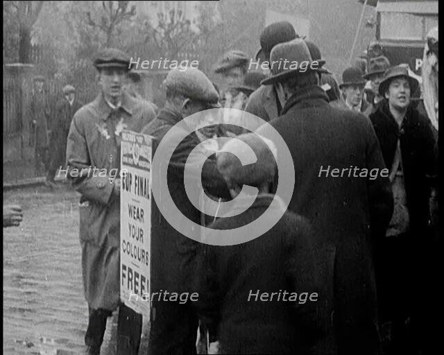 A Man Wearing a Sandwich Board Advertising 'Pathe Gazette' Reading 'Cup Final Wear Your..., 1921. Creator: British Pathe Ltd.