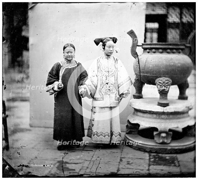 China: a Manchu woman with her maid standing beside a bronze burner, Beijing, 1869. Creator: John Thomson.