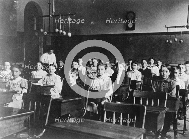 Boys and girls seated at desks in Washington, D.C. classroom, (1899?). Creator: Frances Benjamin Johnston.