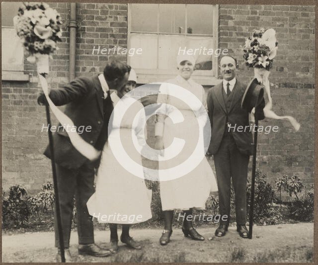 Two men holding tutti poles, with two women during the Hocktide Festival in Hungerford, 1925-35.  Creator: George R Long.