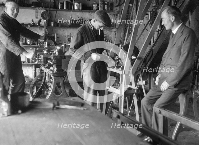 Geoffrey Baker with two other men in a workshop. Artist: Bill Brunell.