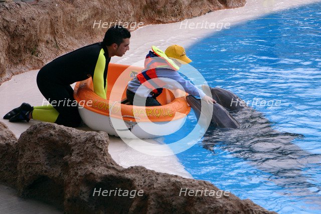 Child petting a dolphin, Loro Parque, Tenerife, Canary Islands, 2007.
