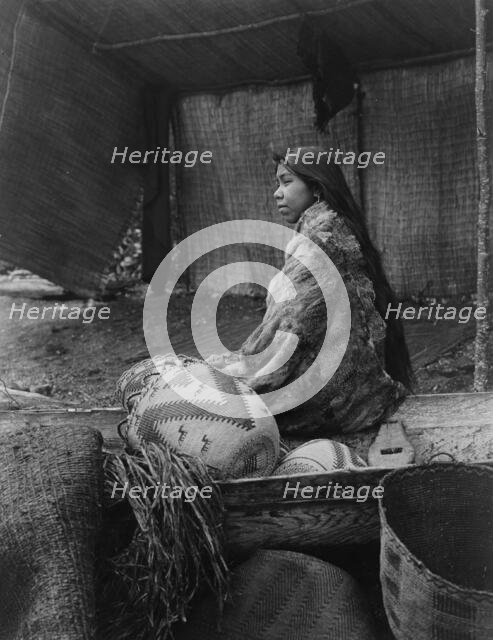 A Skokomish Indian chief's daughter, half-length portrait, seated on canoe, facing left, c1913. Creator: Edward Sheriff Curtis.